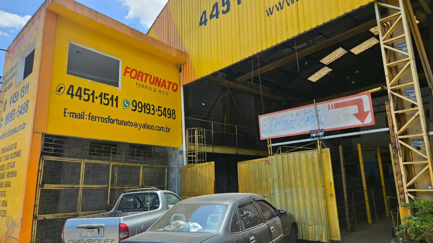 Entrada da loja Fortunato Ferro e Aço: galpão amarelo com o número 2739, os telefones e o e-mail pintados na fachada