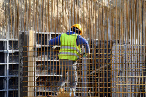 Armador de capacete e colete trabalhando em uma armação de ferragem